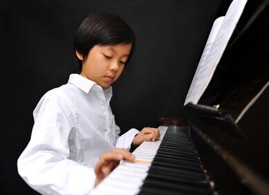 Young boy playing piano (isolated on black background)