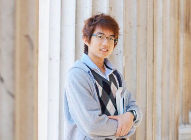 Smiling asian student holding books outdoors