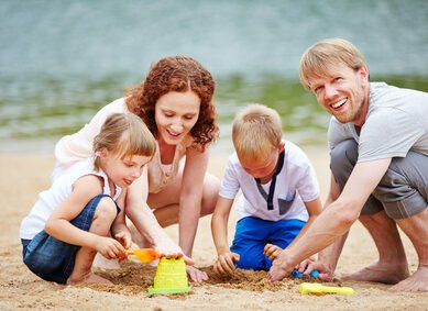 Familie mit Kindern spielt im Sand am Strand