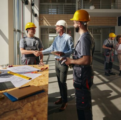 Happy male inspector came to a successful agreement with his worker in a construction building.